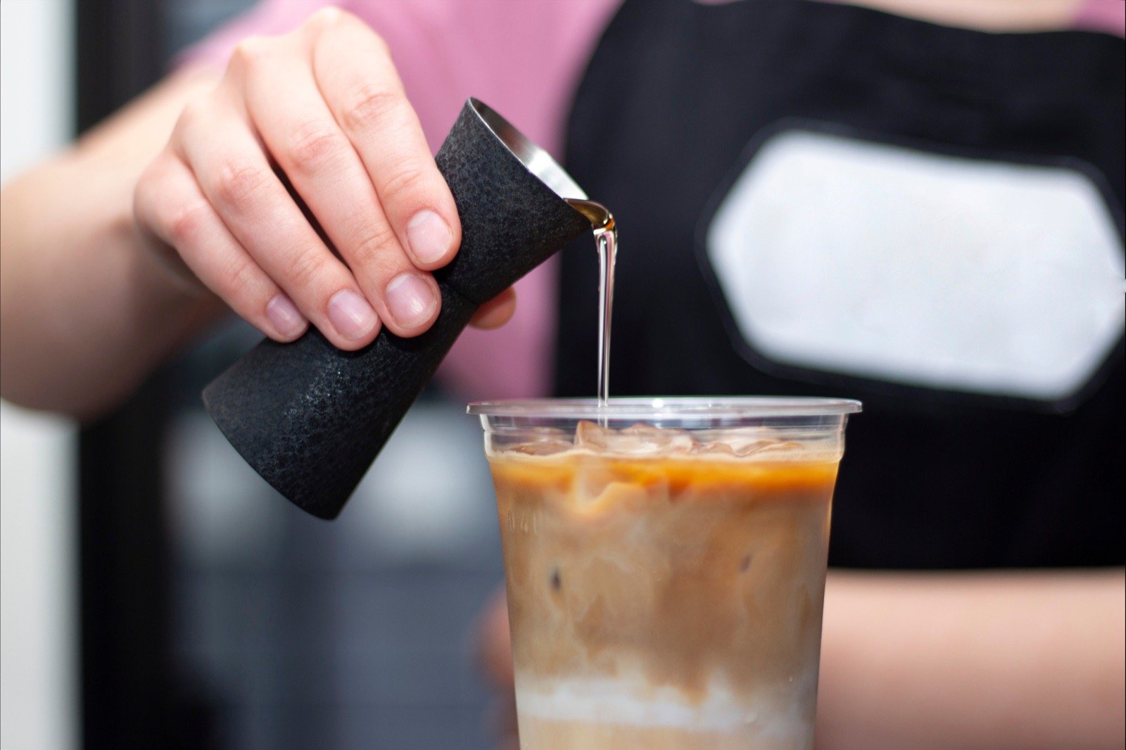 Café staff dosing liquid syrup ingredient into a beverage application