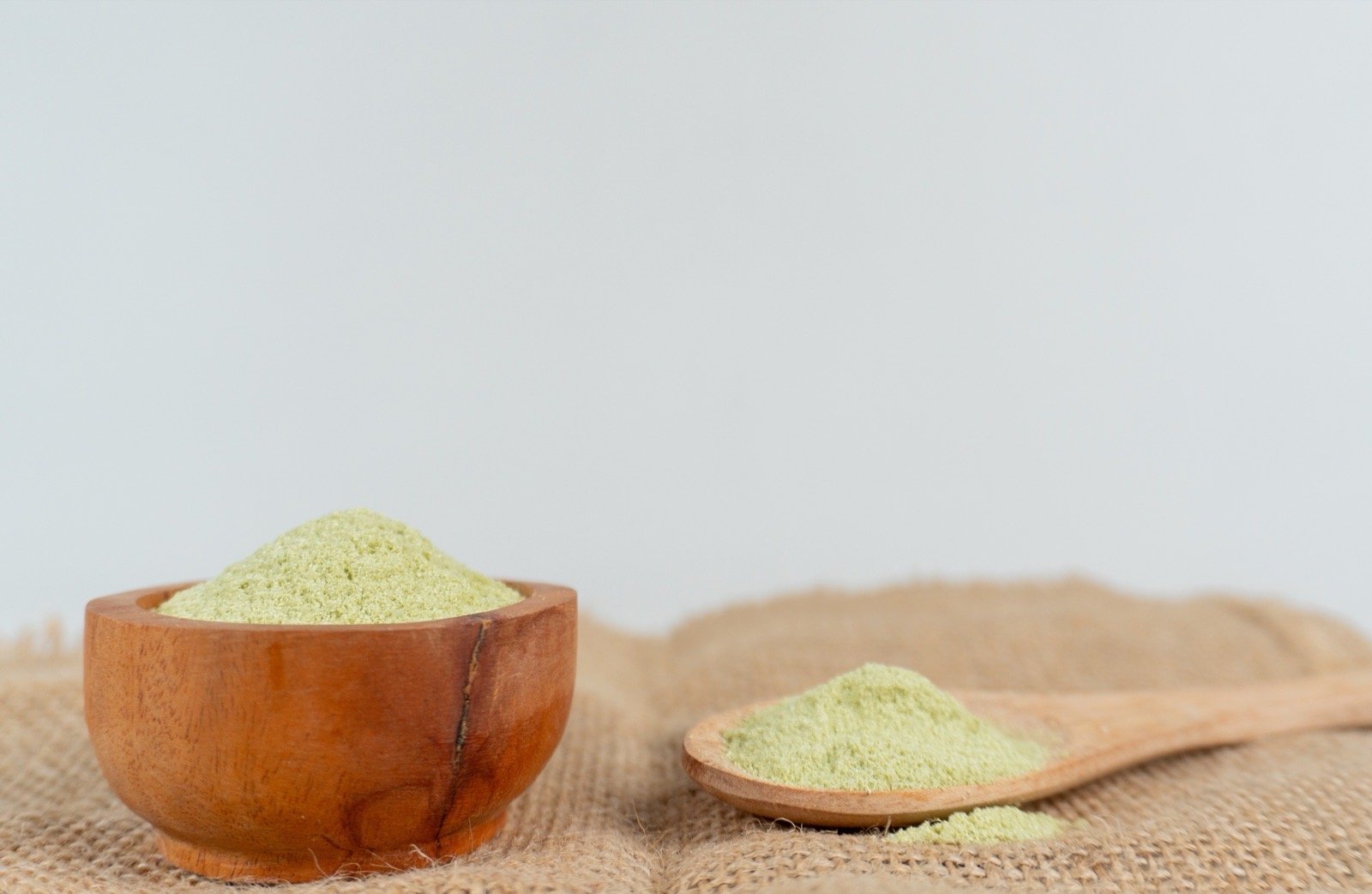 Dry matcha beverage powder ingredient measured with a wooden spoon