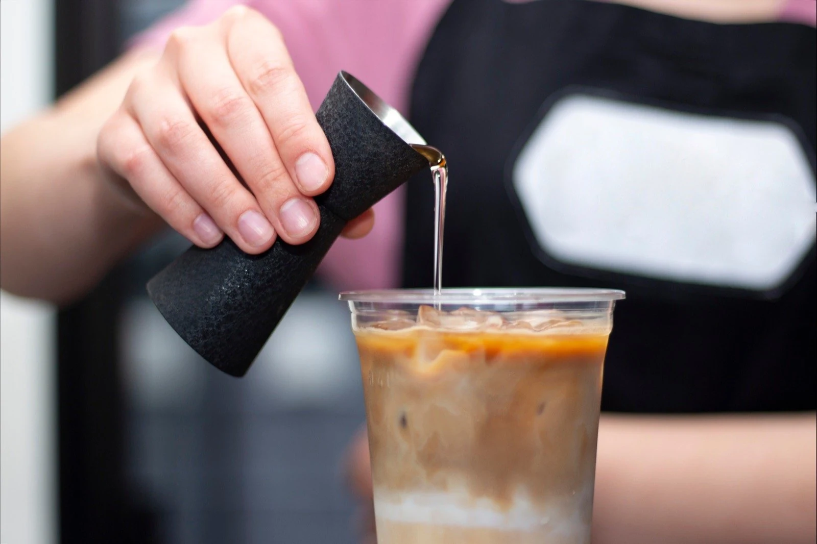 Café staff dosing liquid syrup ingredient into a beverage application